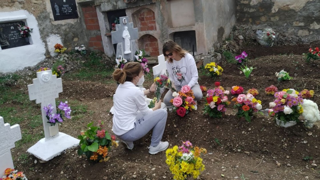 Unas chicas preparan las flores en el cementerio de Riodeva