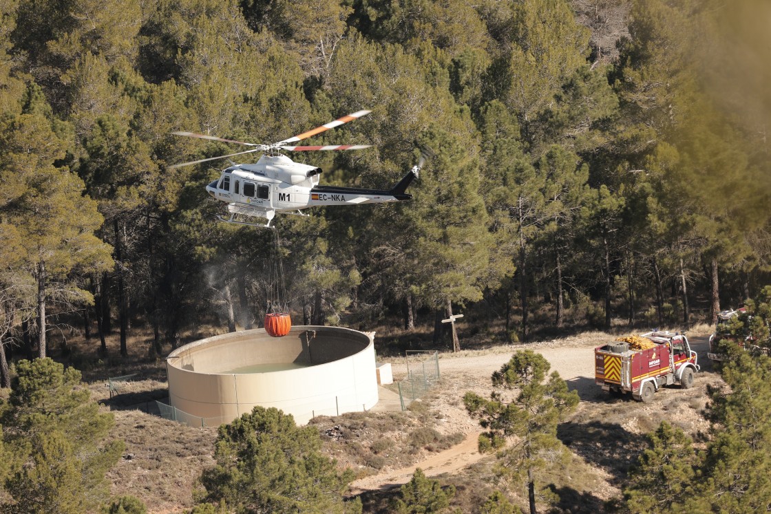 Un helicóptero de extinción de incendios carga agua para tratar de apagar los focos activos en el entorno de San Agustín